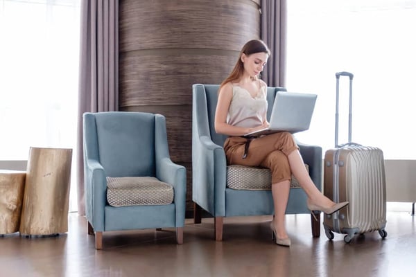 Woman sitting in chair on computer with luggage