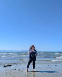 Carly Fielding, For-Sight Marketing Assistant, standing on a sandy beach on a sunny day.