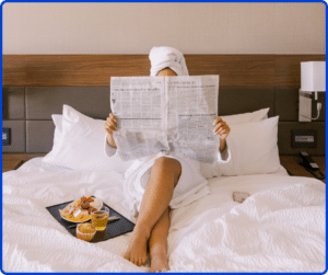 Woman reading newspaper in hotel bed
